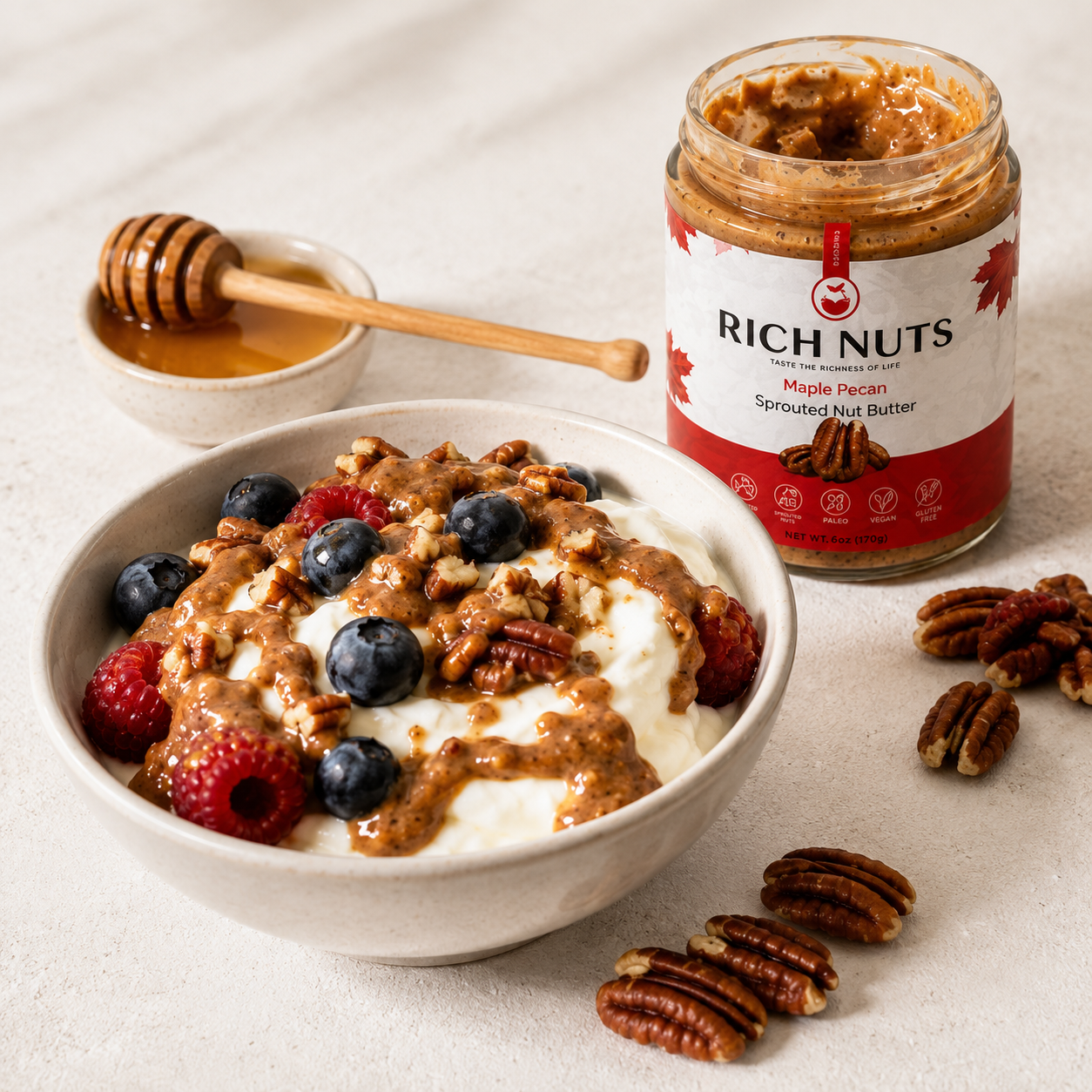 Maple Pecan Sprouted Nut Butter drizzled over a yogurt bowl with blueberries, raspberries, pecans and honey